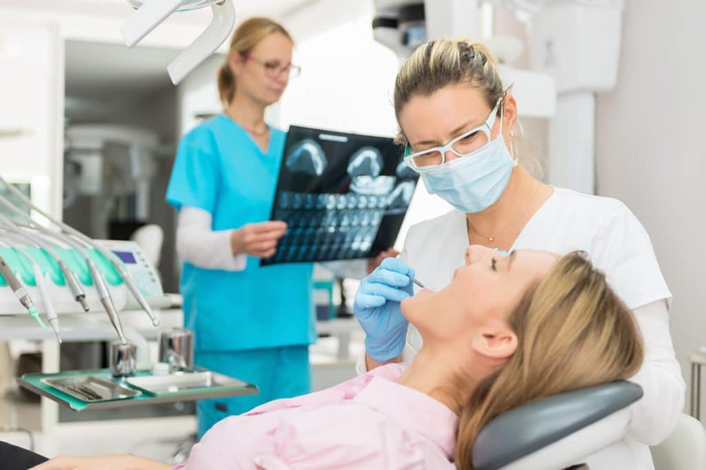 dental procedure taking place with X-rays in background