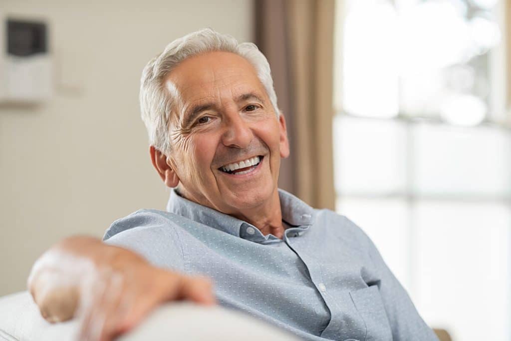 mature man smiles from couch