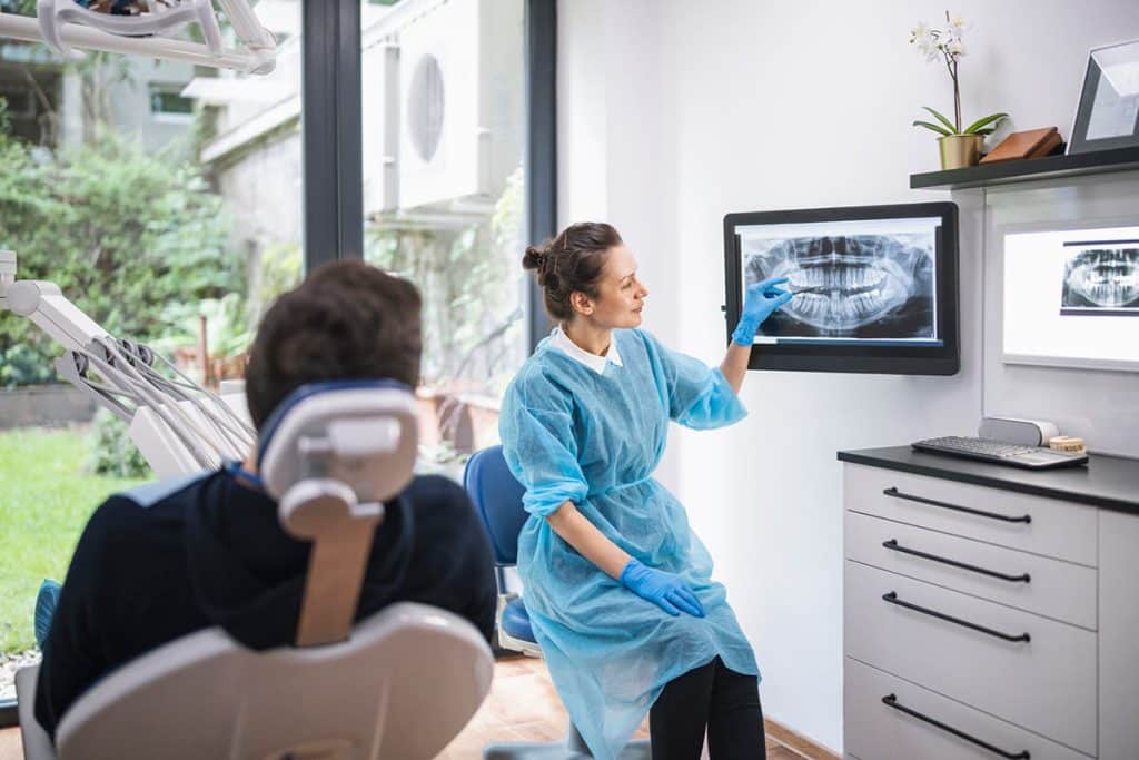 dentist shows patient digital image of X-rays